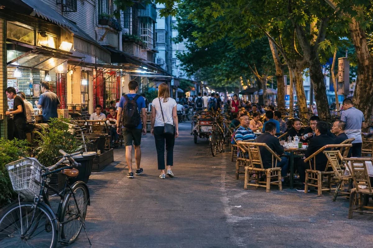 Travelers walking through a lively Chengdu neighborhood with tea tables and local restaurants