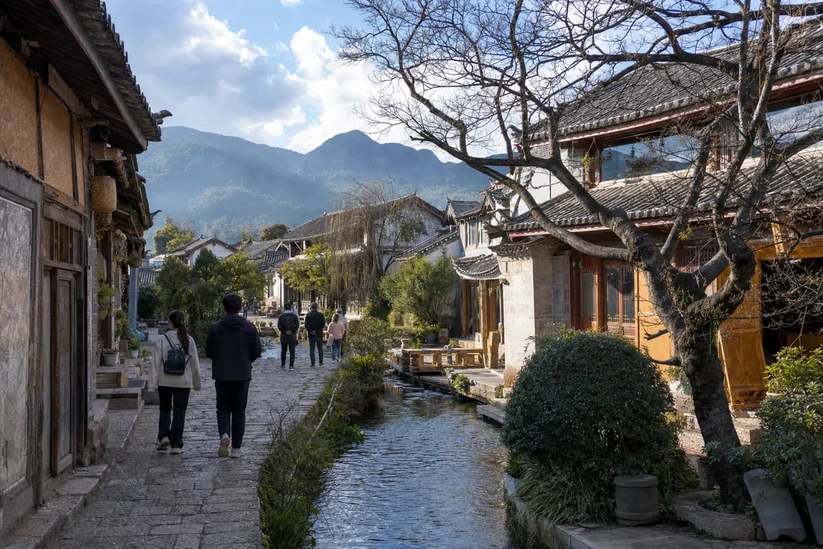 A Lijiang Old Town lane and water channel below the hills.