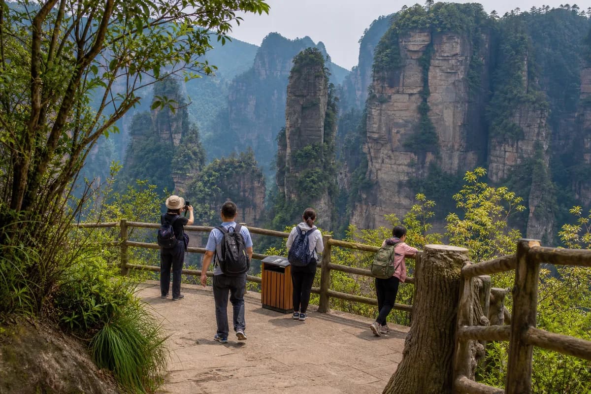 A maintained Zhangjiajie park path facing forested sandstone pillars.